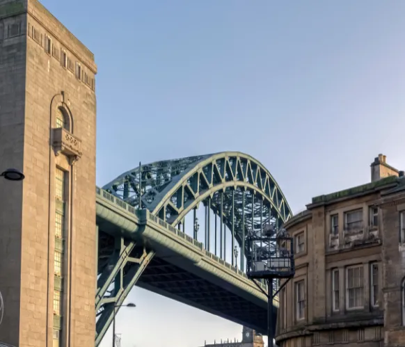 Tyne Bridge in Newcastle, iconic steel arch bridge between historic city buildings at sunset.